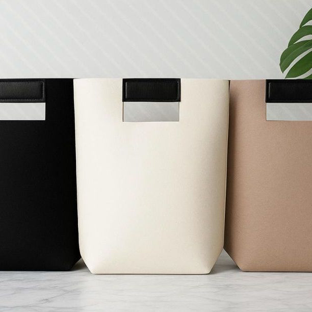 Felt gift bag with brown leather handles and beige fabric construction