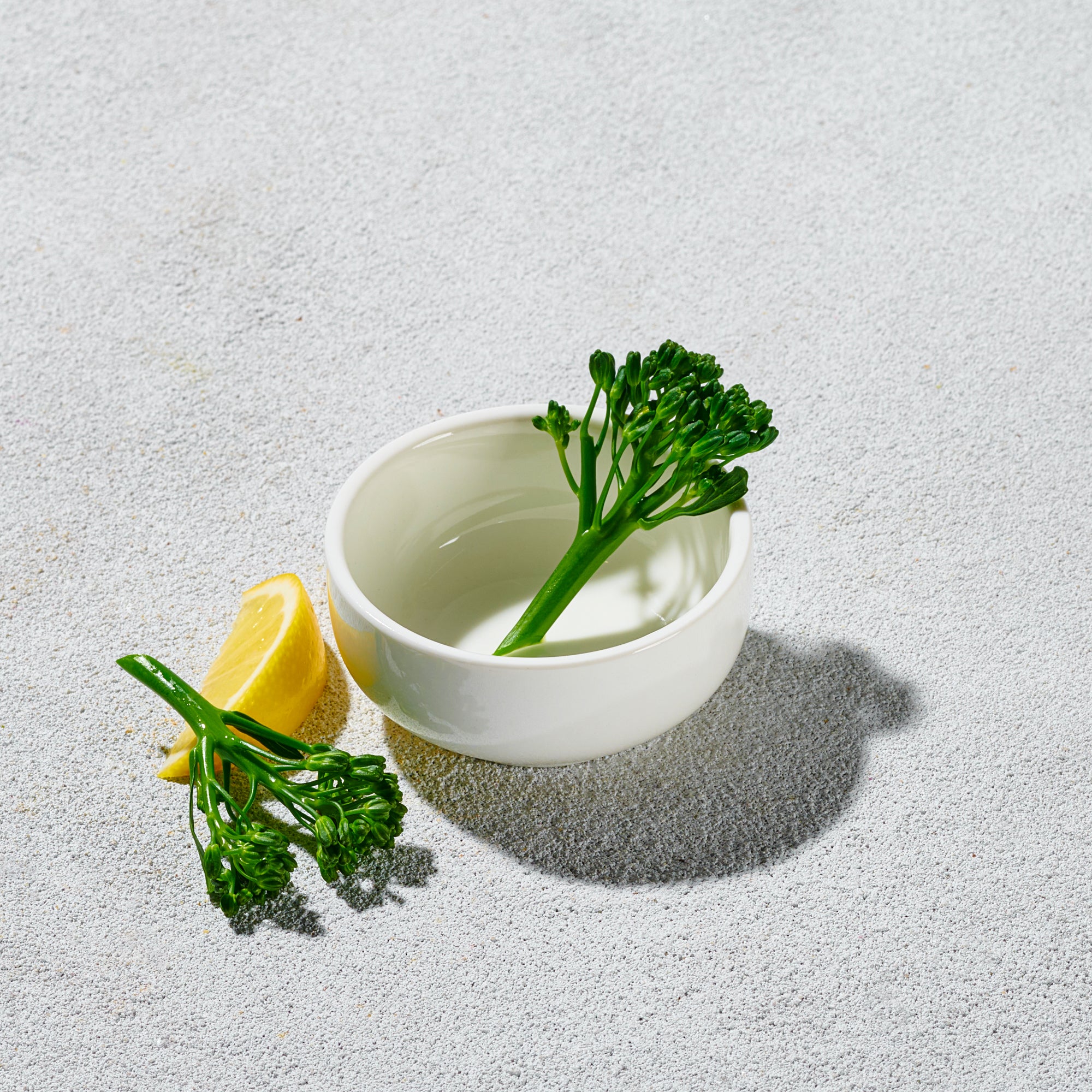 White bowl with green leafy vegetable on a light gray background